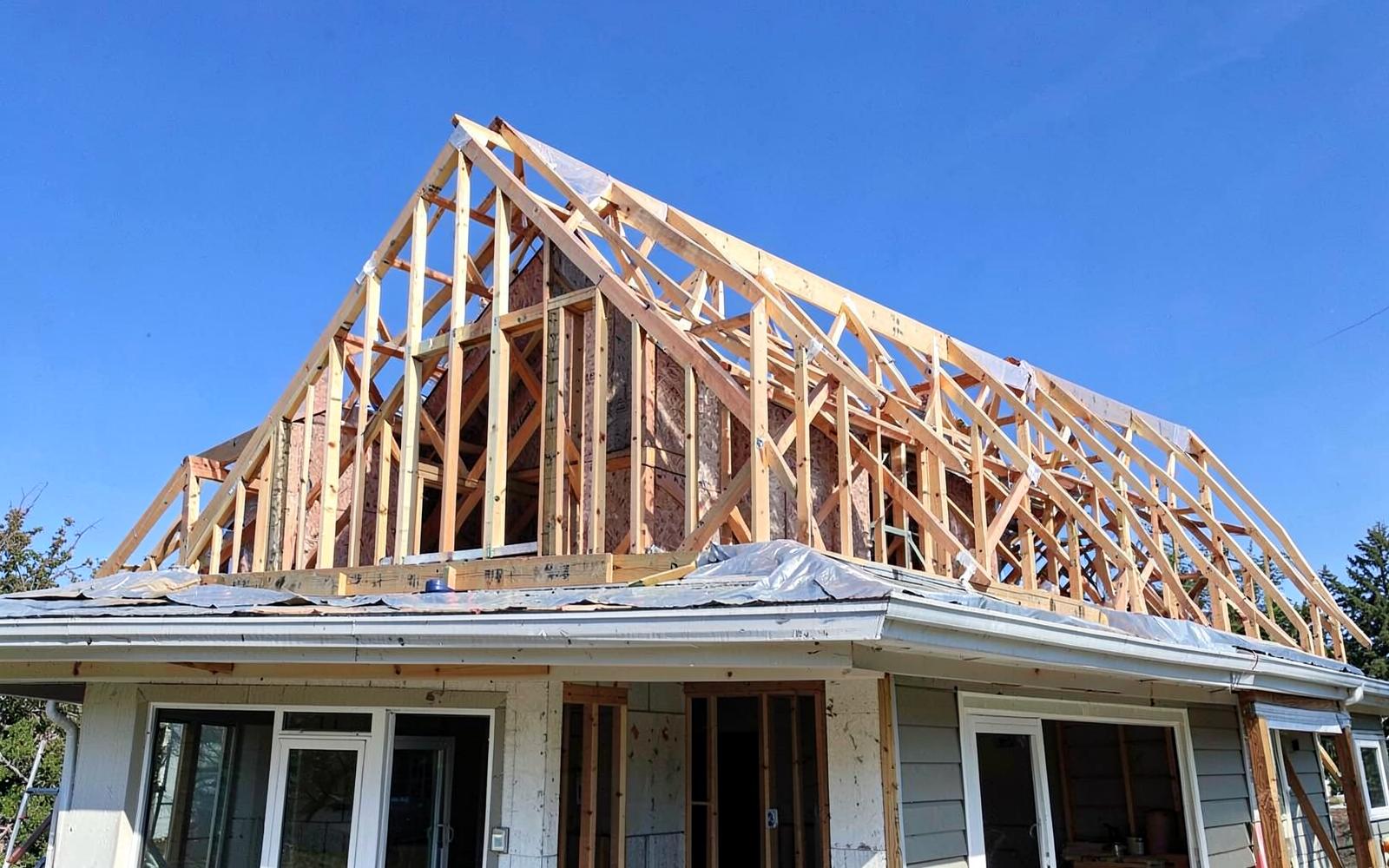 Second floor framing with wall studs and roof trusses under weather wrap