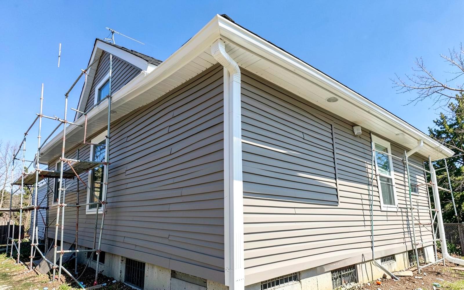 Side house extension exterior with new siding, fascia and gutters going up